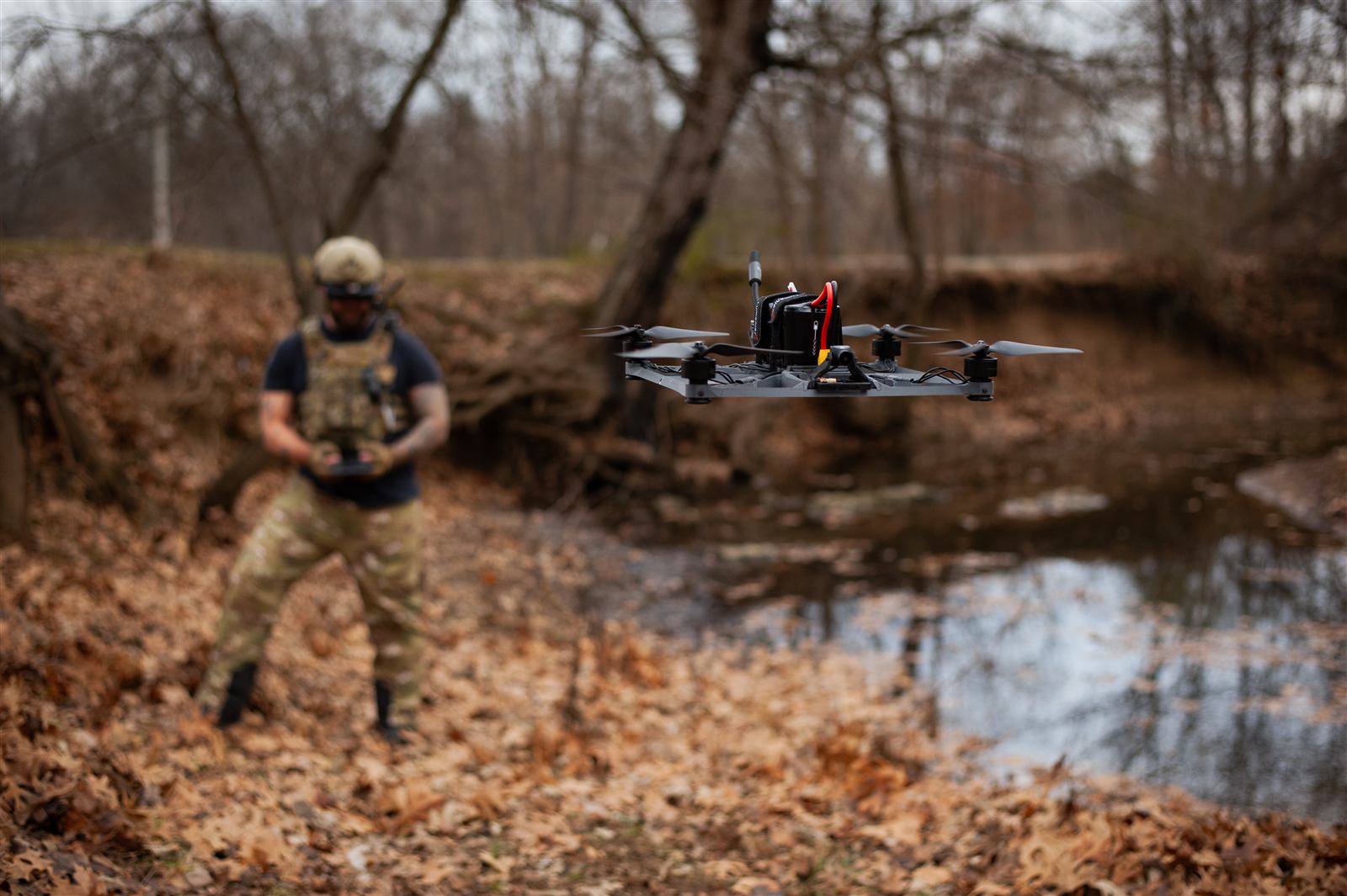 Operator flying a REAVERS drone over a creek